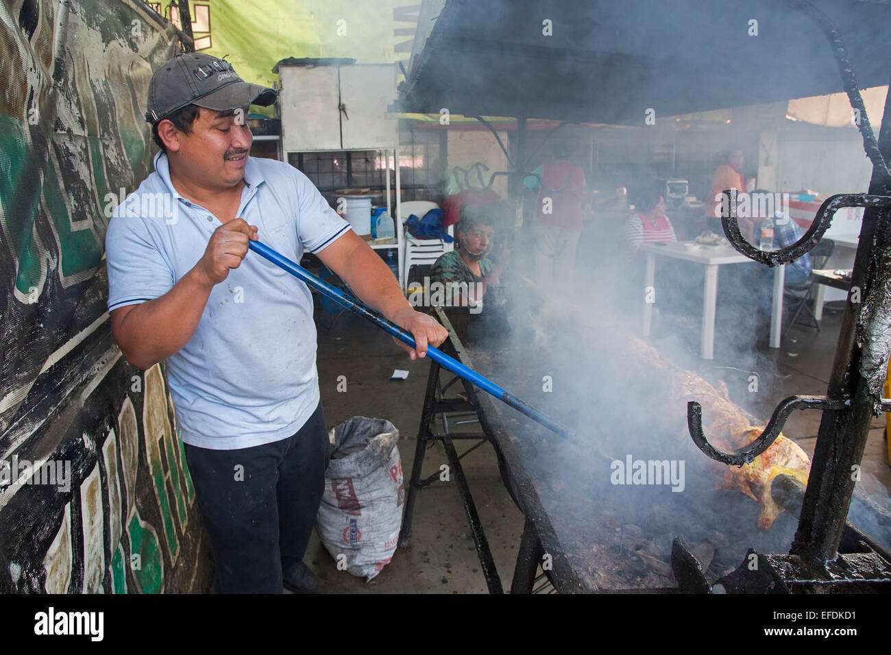 Oaxaca, Mexique - Un homme cuisiniers viande à un incendie dans un restaurant en plein air. Banque D'Images