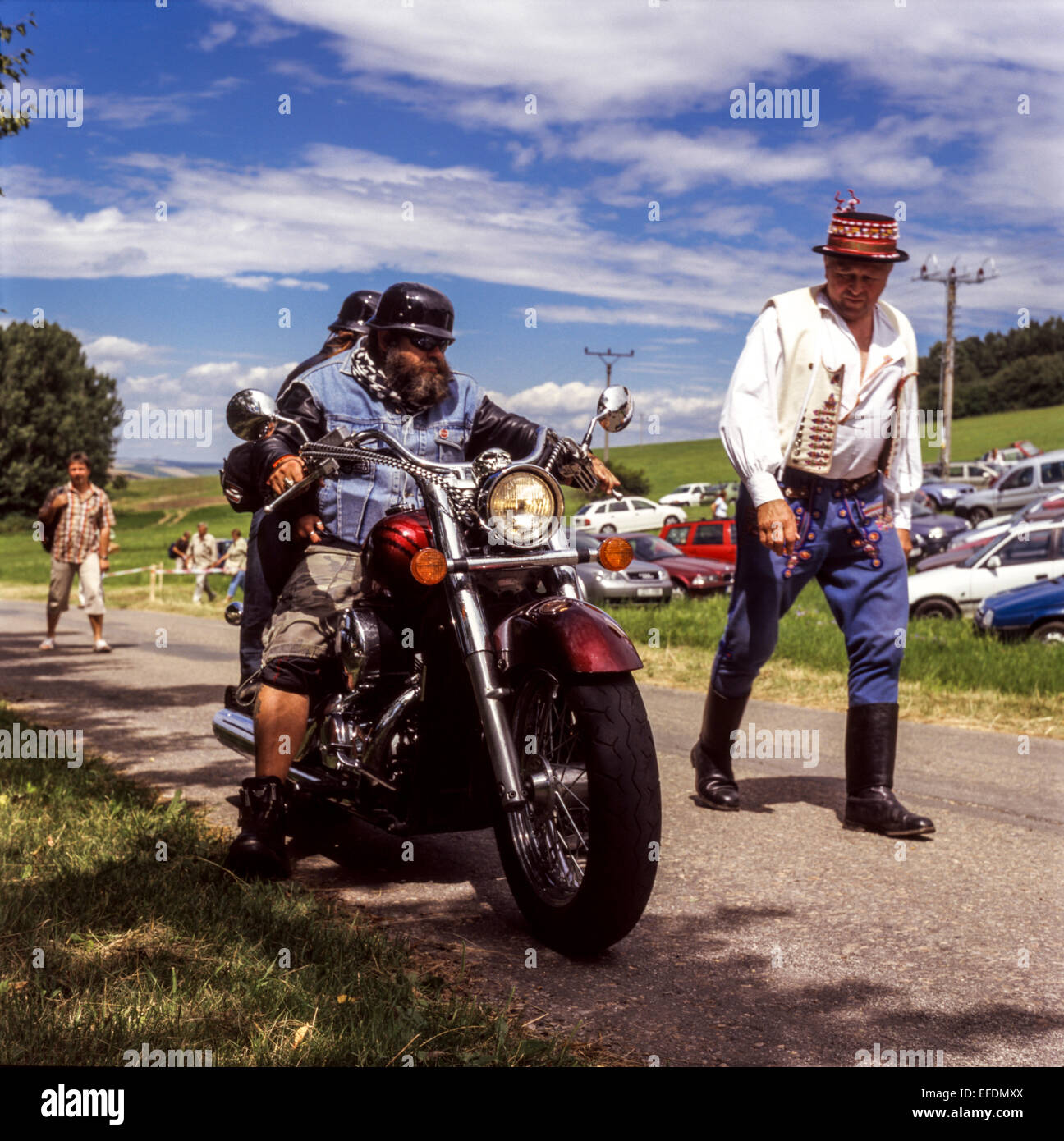 Homme âgé en costume folklorique passant devant les fans de moto, Moravie, République tchèque Banque D'Images