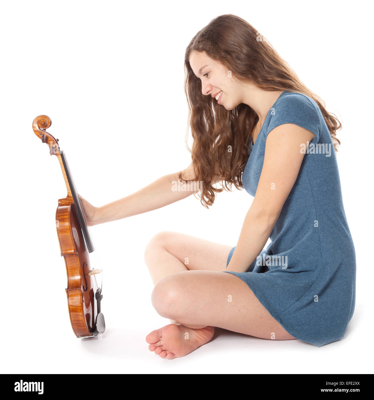 Teen brunette wearing robe siège avec violon en studio against white background Banque D'Images
