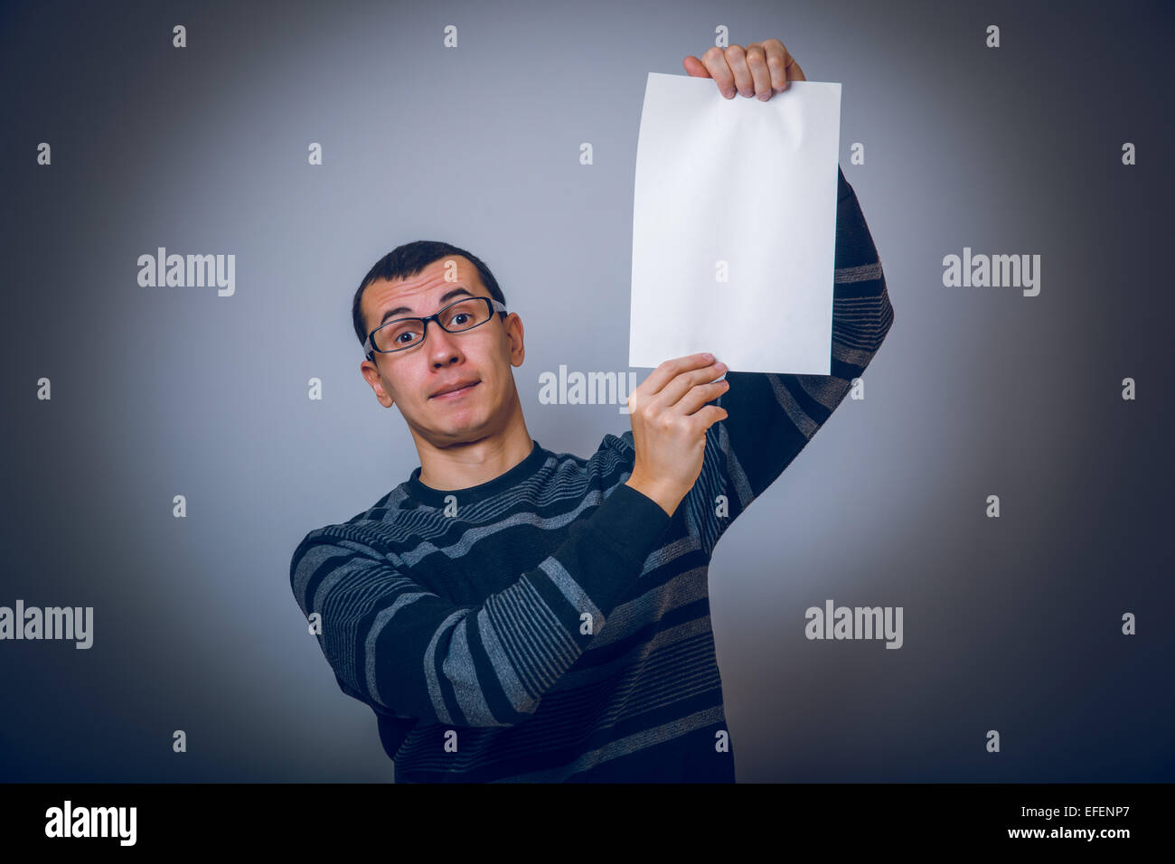 Homme européen tenant une feuille de papier blanc sur gris Banque D'Images