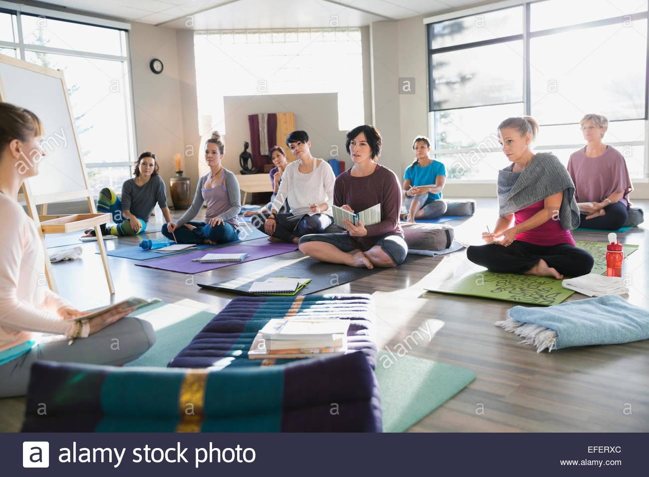 Les femmes avec des journaux à la retraite de yoga réparatrice Banque D'Images
