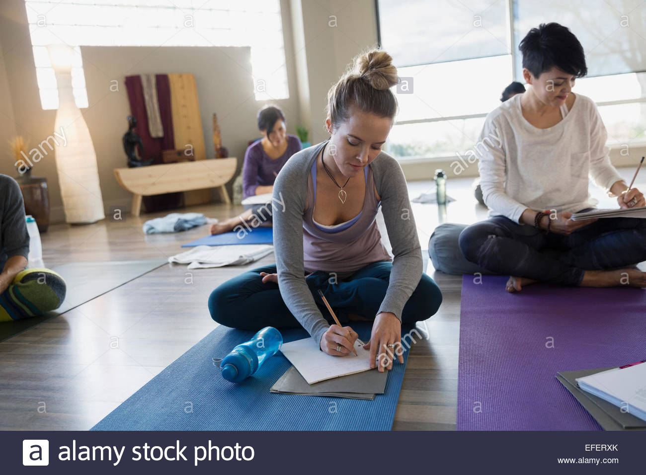 Les femmes avec des journaux à la retraite de yoga réparatrice Banque D'Images