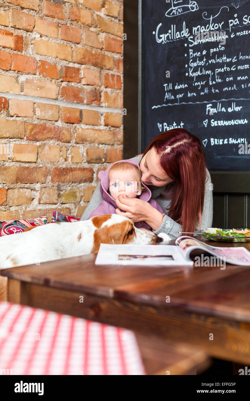 Jeune femme nourrir bébé fille avec basset-hound au cafe table Photo Stock  - Alamy