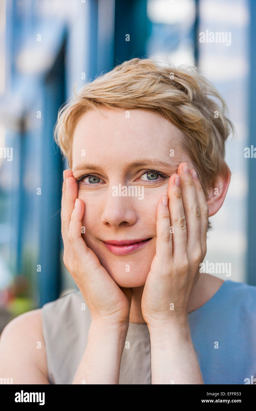 Portrait of smiling blonde femme avec les mains sur son visage Banque D'Images