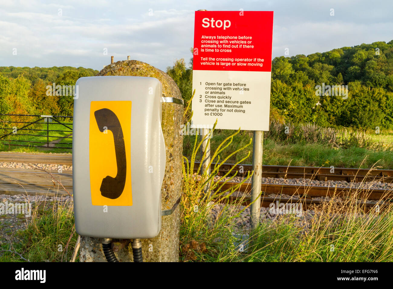 Téléphone et panneau d'arrêt à un passage à niveau non protégé et sans pilote sur une ligne de chemin de fer dans la campagne, Lancashire, England, UK Banque D'Images