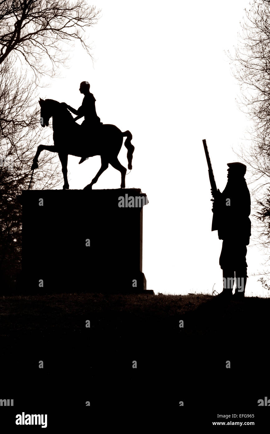 Le noir et blanc silhouette d'homme tenant un fusil de chasse à la recherche jusqu'à la statue de cavalier à West Wycombe park, españa Banque D'Images