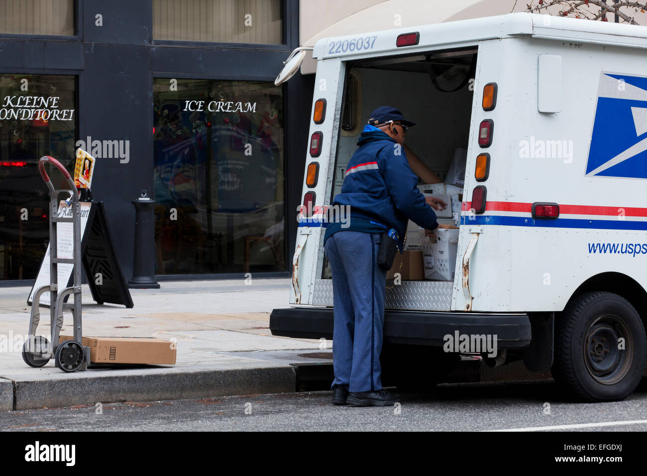 Mailman nous travailler derrière des camions de livraison - USA Banque D'Images