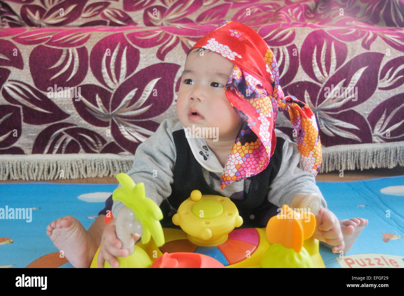 Mignon Bébé Garçon chinois avec foulard sitting on floor and playing with  toy Photo Stock - Alamy