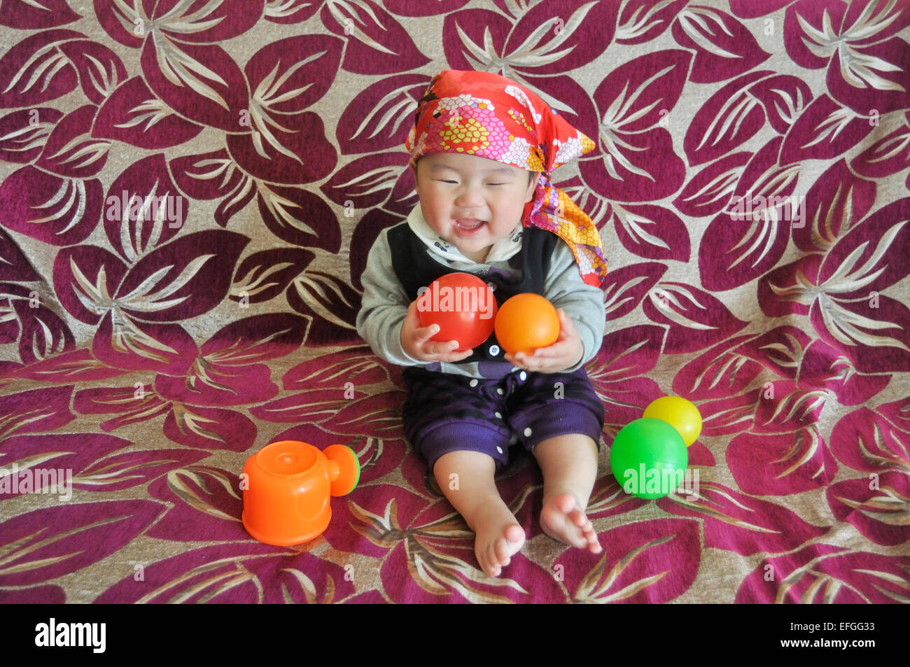 Happy asian baby boy avec foulard sitting on sofa Banque D'Images