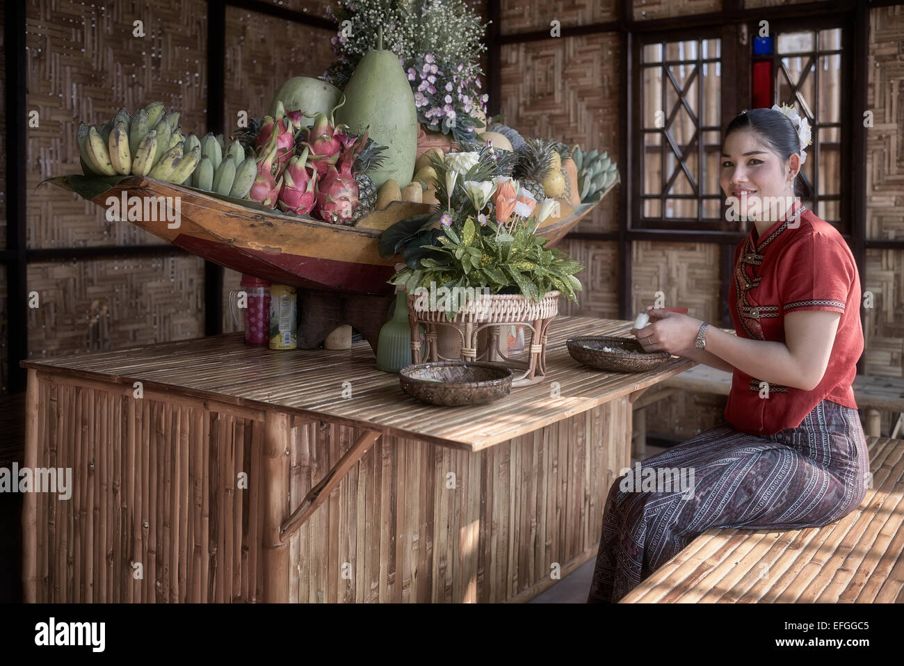 Thaïlande artisanat. Femme en robe traditionnelle avec exposition de fruits et de fleurs dans un centre artistique et culturel thaïlandais. Thaïlande S. E. Asie Banque D'Images