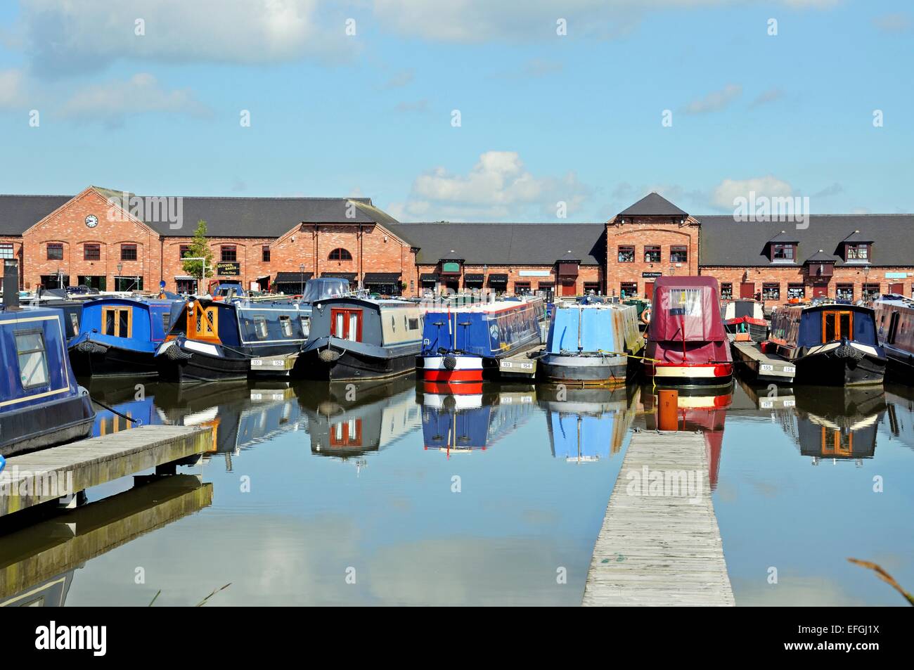 Narrowboats sur leurs amarres dans le bassin du canal, avec des magasins, bars et restaurants à l'arrière, Barton en vertu de Needwood. Banque D'Images