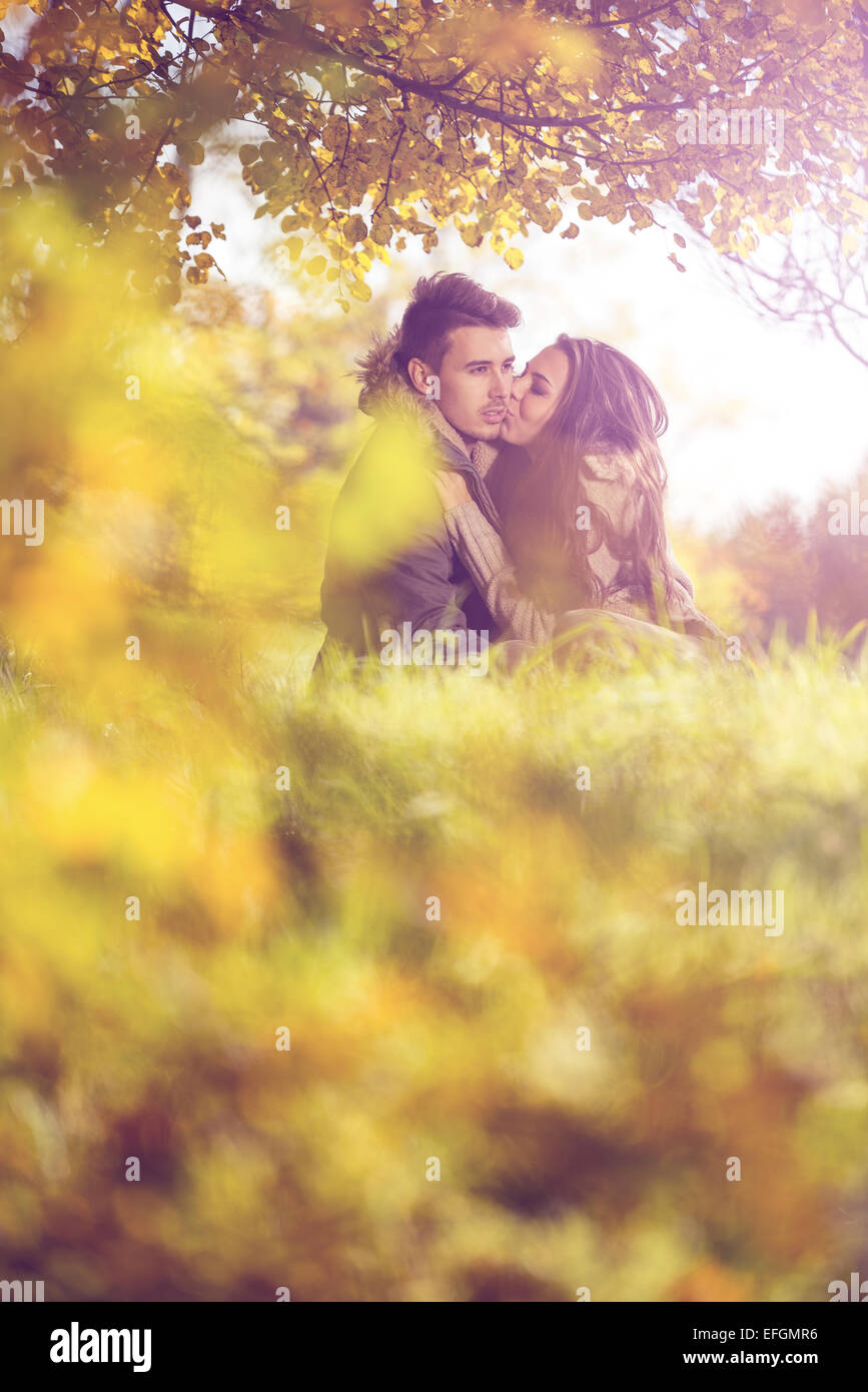 Love couple embrasser sous un arbre dans le parc de l'automne Banque D'Images