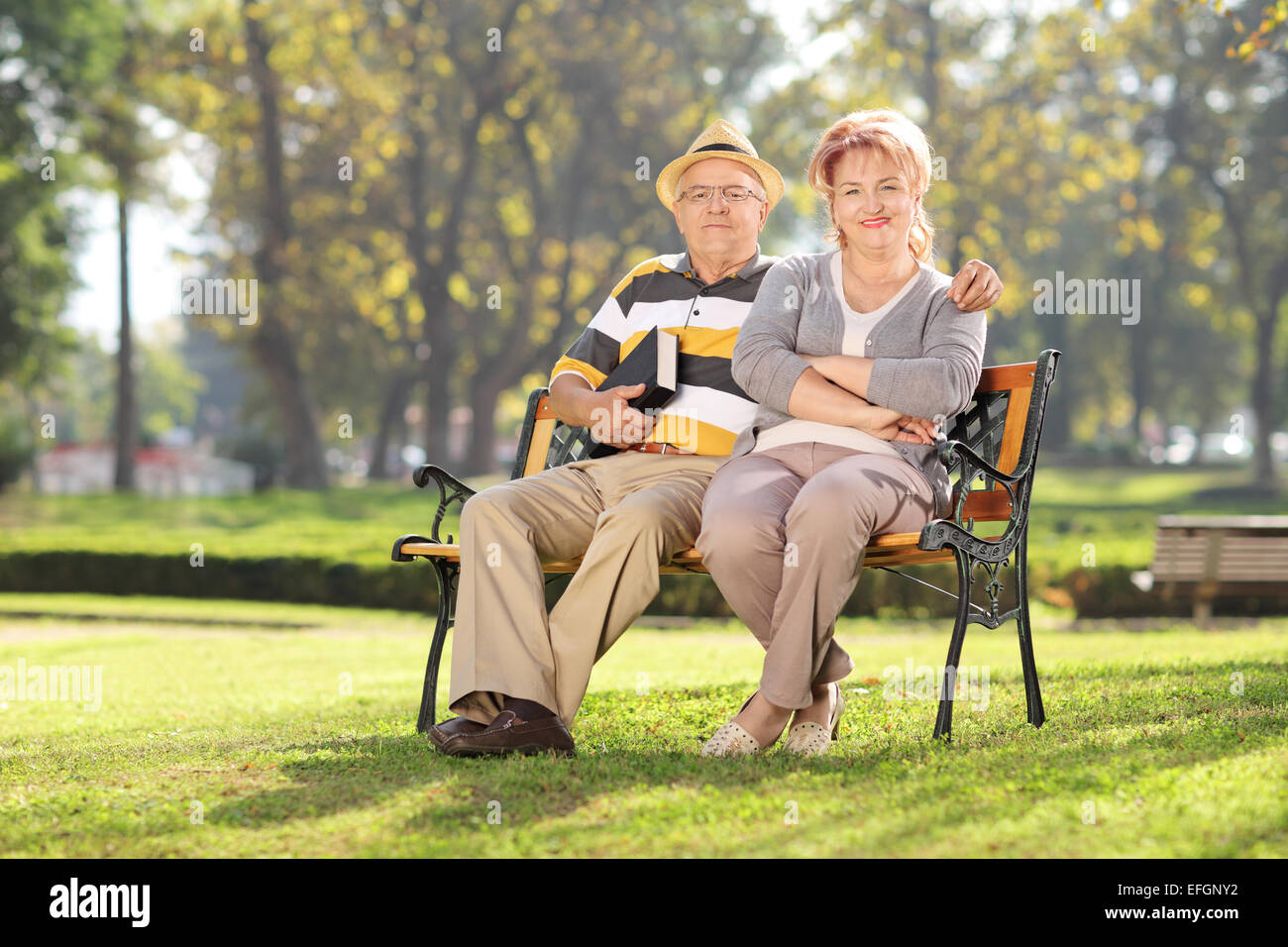 Couple d'âge mûr assis sur un banc de parc sur une journée ensoleillée Banque D'Images