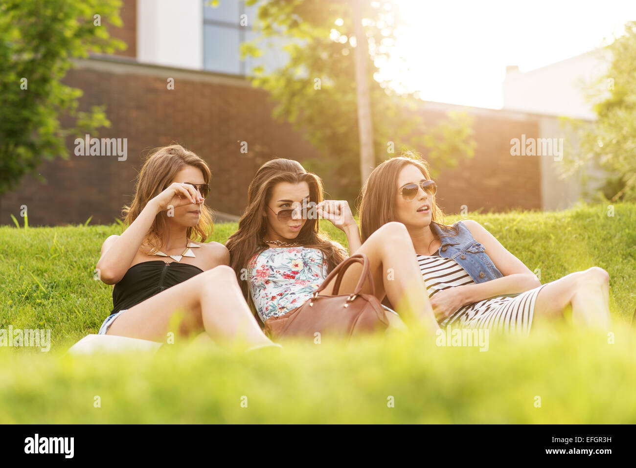 Trois belles woman looking at the beaux hommes dans l'herbe Banque D'Images