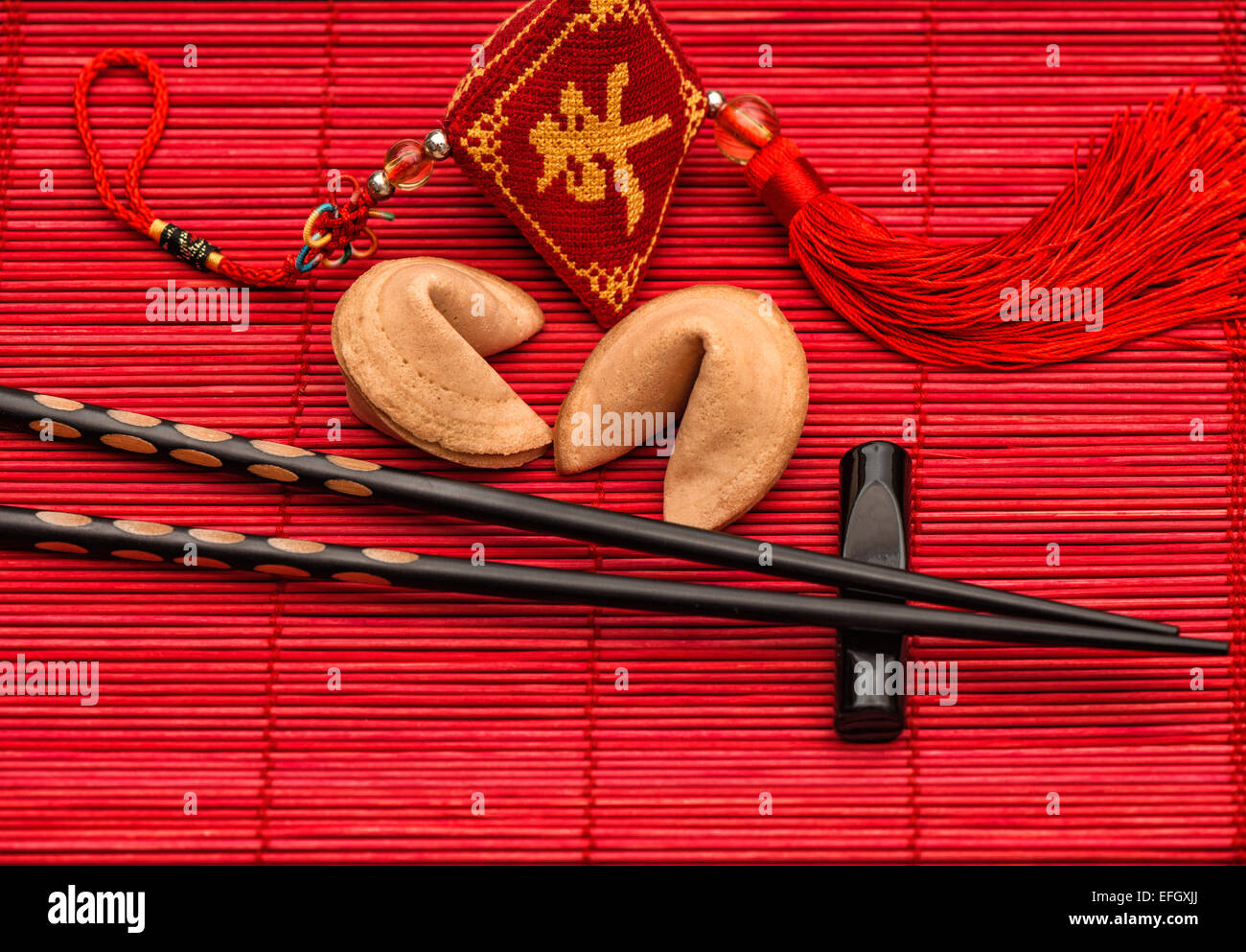 L'Asie fête fond style avec Lucky Charm, fortune cookies et Baguettes en bambou noir sur rouge mat. Concept du nouvel an chinois Banque D'Images