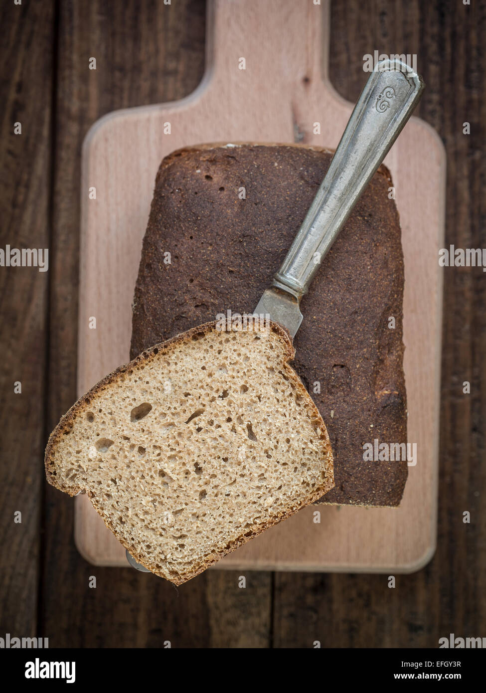 Des grains de blé-seigle mixte pain au levain sur une planche à découper. Banque D'Images