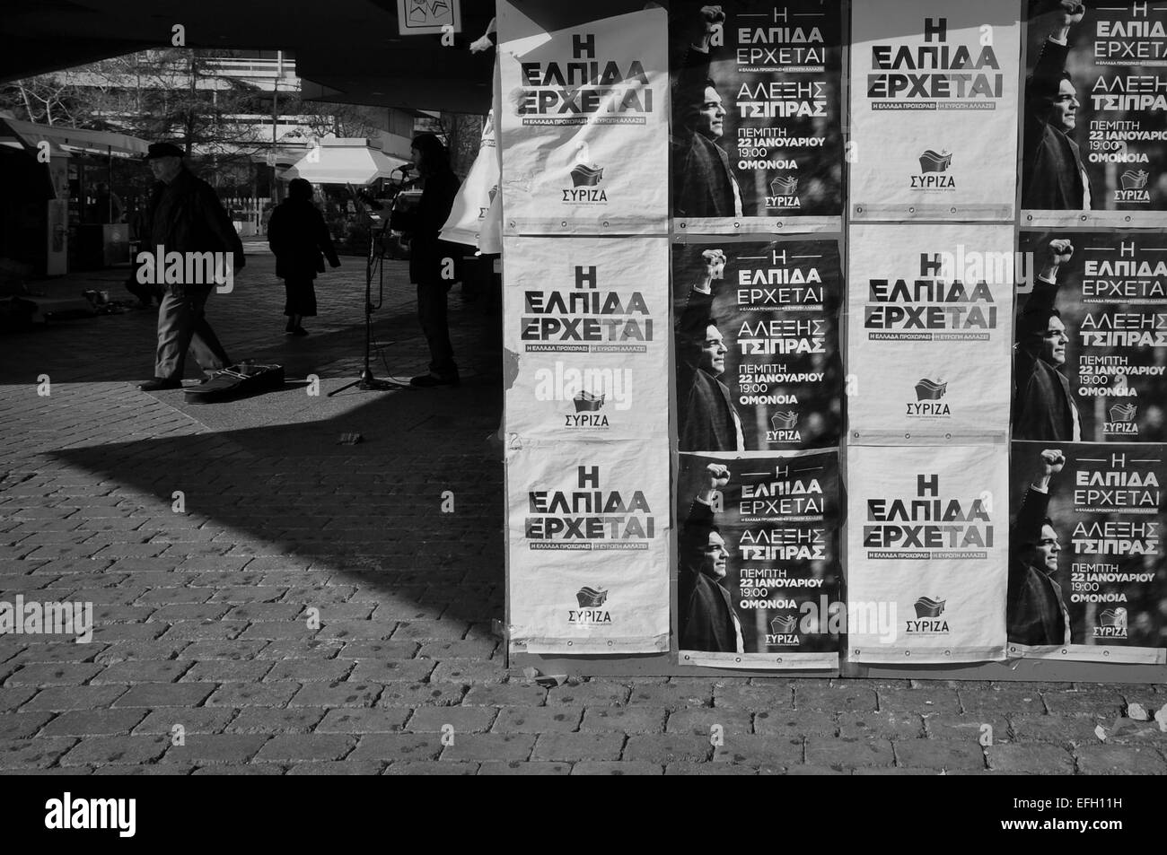 Des affiches de nouveau premier ministre de la Grèce sur Syriza, Alexis Tsipras, kiosque de la campagne. Musicien de rue et les gens en noir et blanc. Banque D'Images