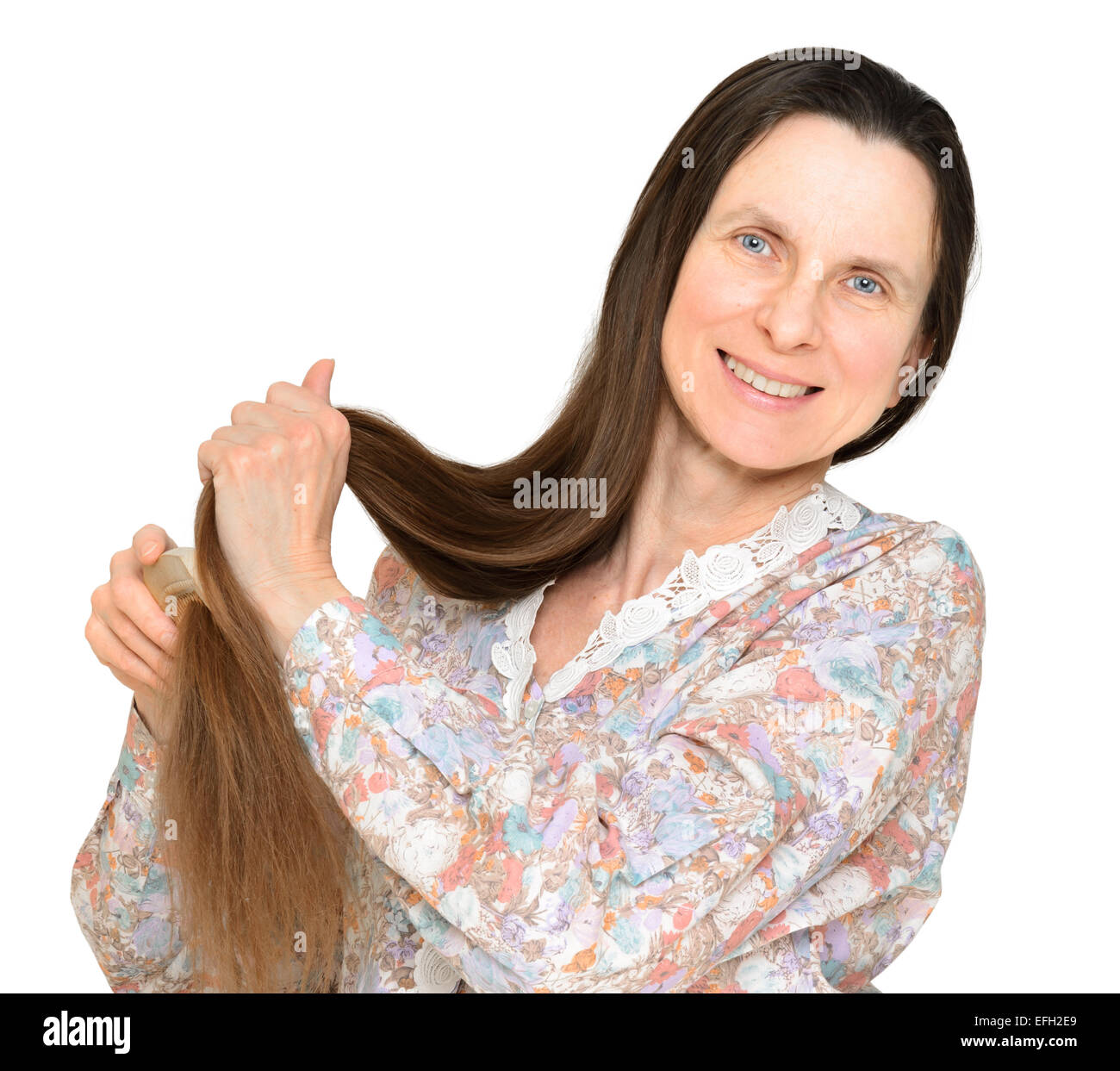 Hot woman combing longs cheveux bruns avec un peigne en bois, isolé sur fond blanc Banque D'Images