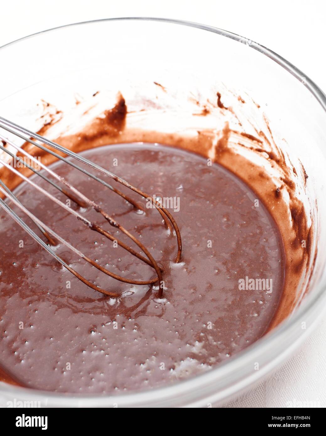 Le mélange d'une pâte de chocolat dans un bol en verre pour faire un gâteau. Banque D'Images