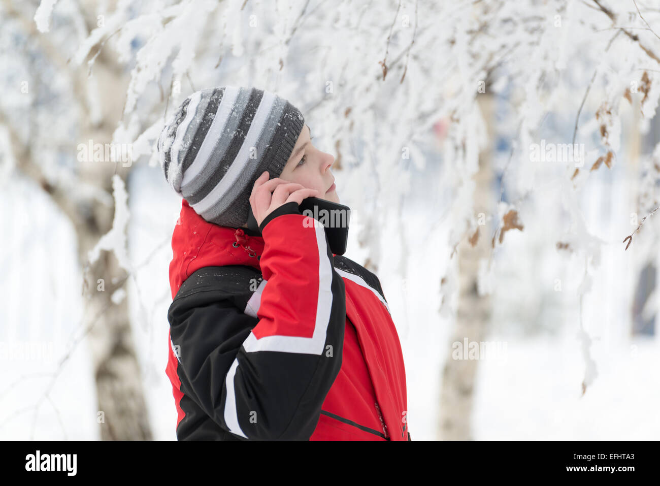 Teen boy à parler au téléphone dans winter park Banque D'Images