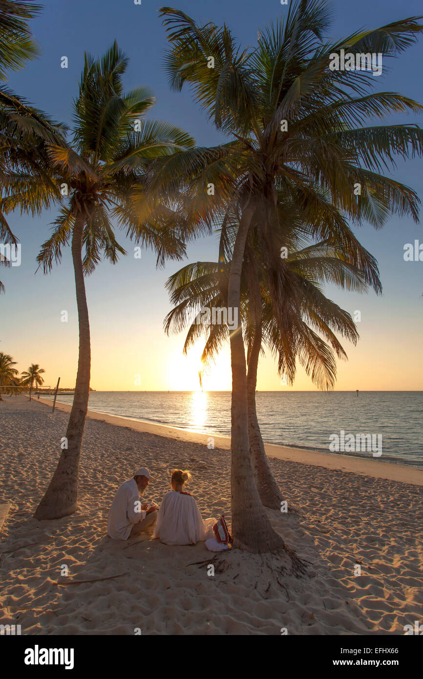 Couple sitting at sunrise sur Smathers Beach Key West, Key West, Florida Keys, Floride, USA Banque D'Images