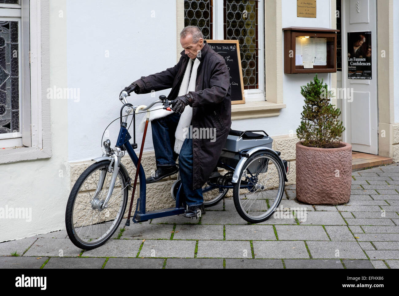 Un homme handicapé âgé qui roule sur un vélo tricycle Banque D'Images