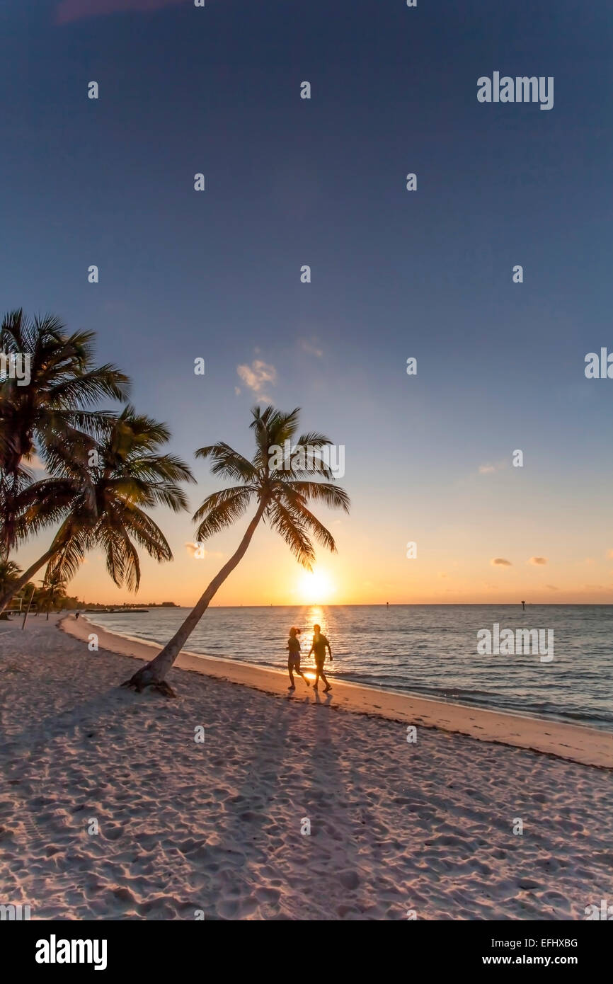 Matin impression avec couple jogging le long de la plage au lever du soleil, Smathers Beach Key West, Key West, Florida Keys, Floride, USA Banque D'Images