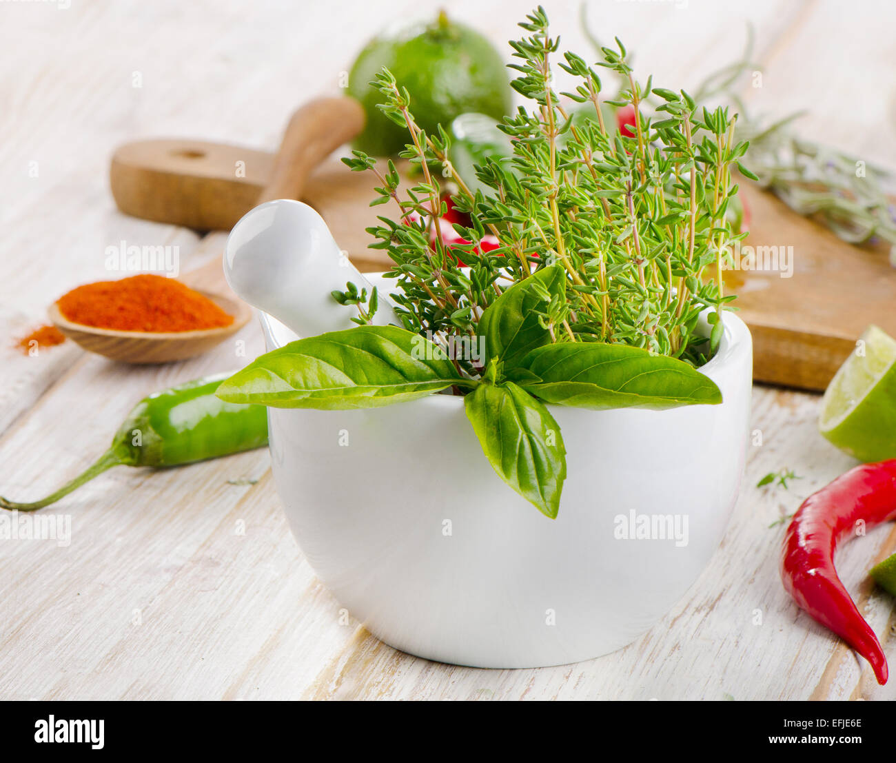 Le mortier avec des herbes et les poivrons rouges sur une table en bois. Selective focus Banque D'Images