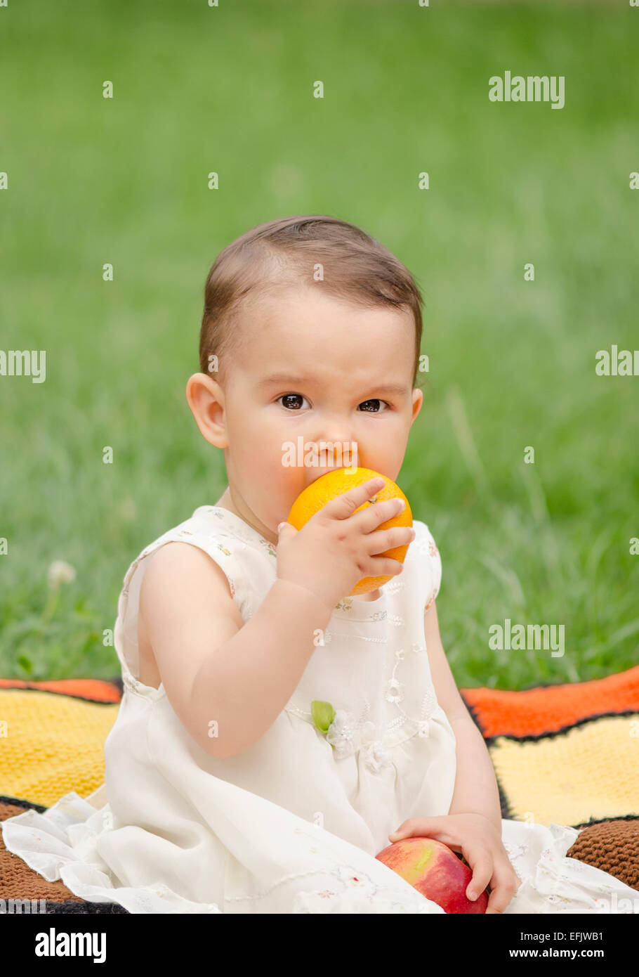Cute little girl eating une orange Banque D'Images