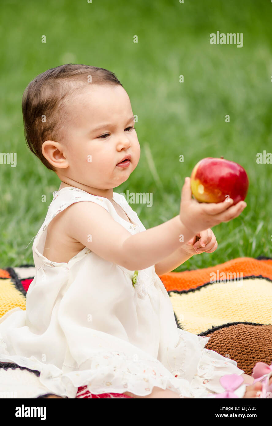 Cute little girl eating a red apple Banque D'Images