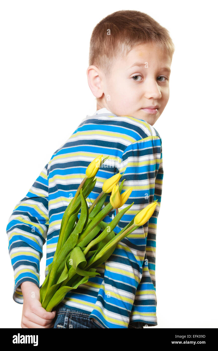 Maison de vacances concept de la fête des mères. Petit garçon a préparé un cadeau surprise pour maman, fleurs tulipes jaunes, les conserve dans le dos Banque D'Images