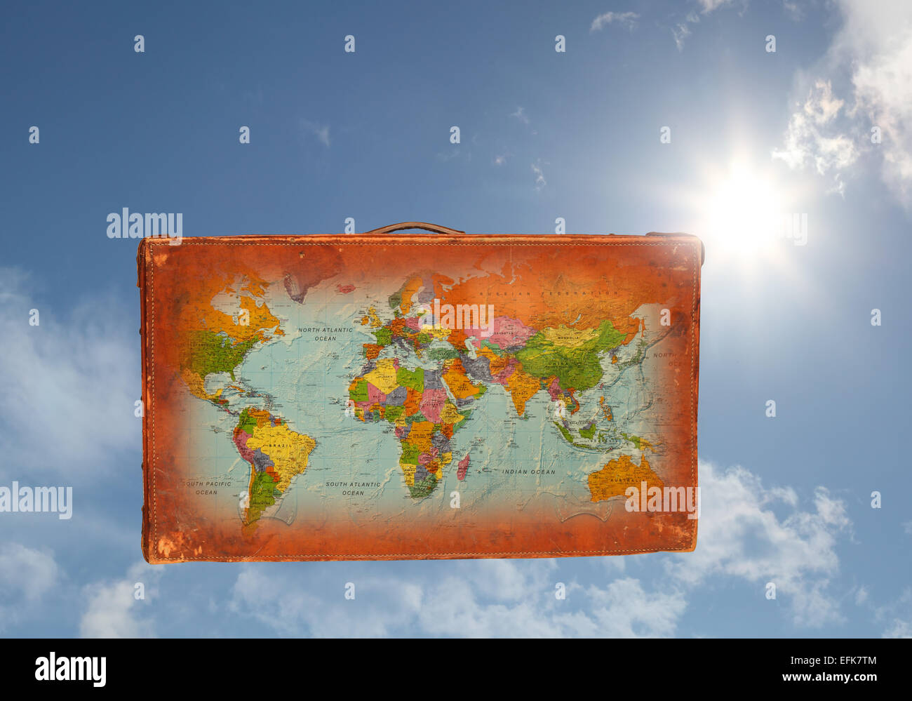 Une vieille valise en cuir avec une carte du monde superposées, indiqué contre un ciel bleu ensoleillé Banque D'Images