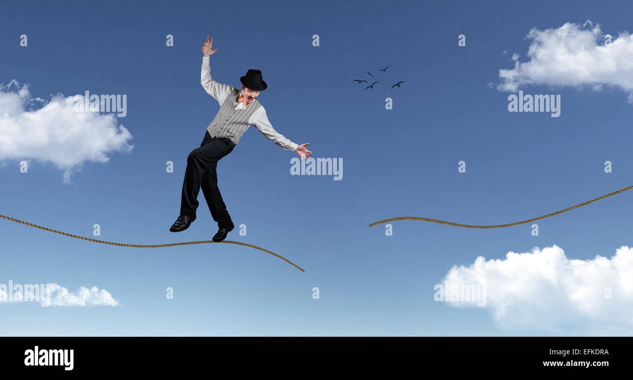 Ropewalker en noir hat standing sur corde rompue dans le ciel bleu avec des nuages Banque D'Images