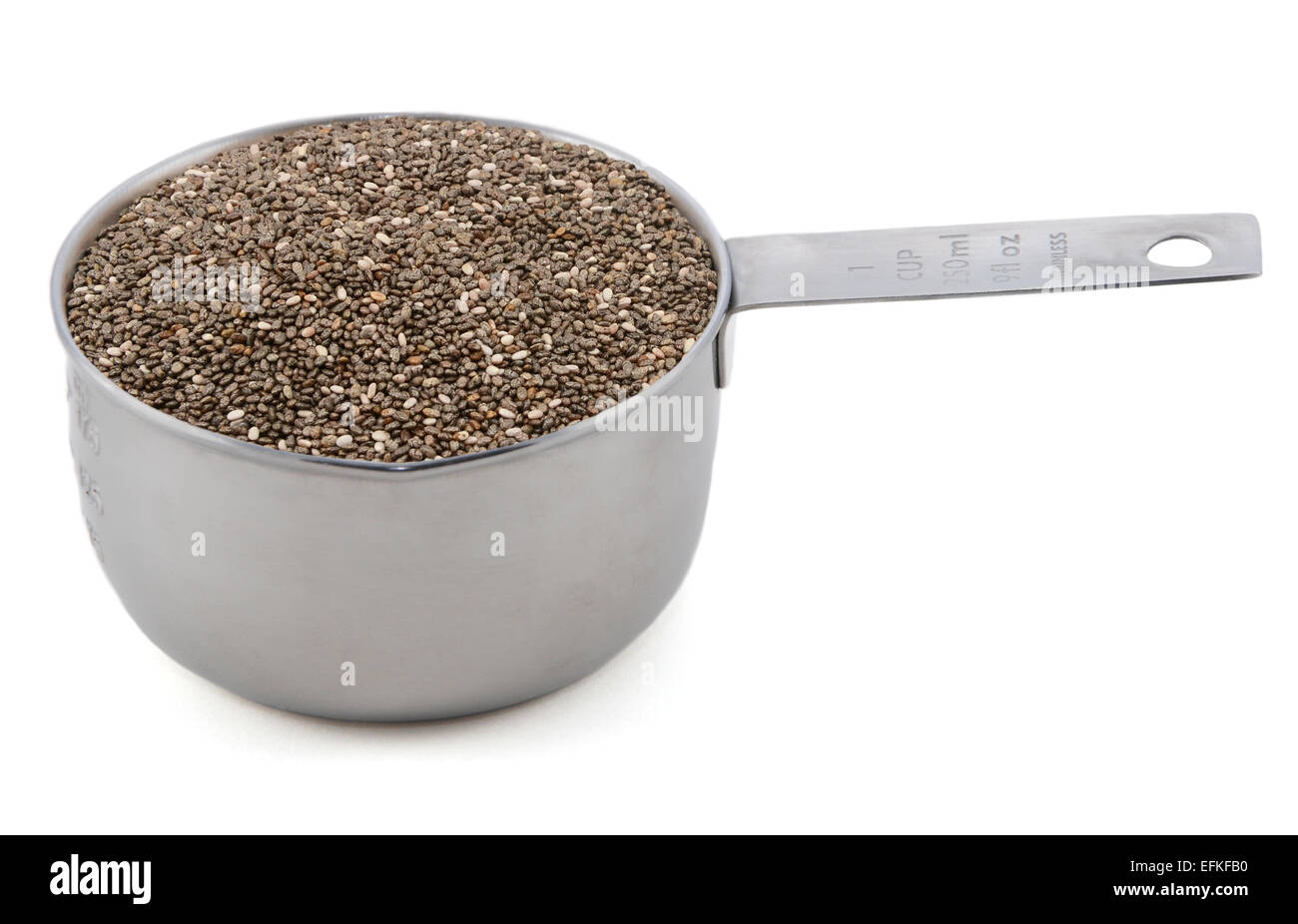 Les graines de Chia dans un tasse mesurer, isolé sur fond blanc Banque D'Images