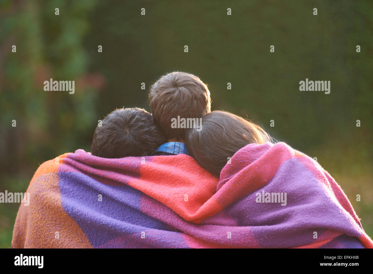 Frères et sœurs enveloppée de blanket in garden Banque D'Images