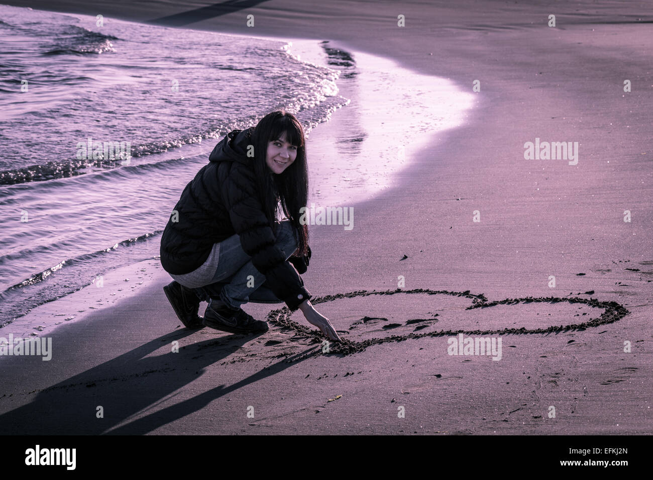 Le Portrait D Une Jolie Fille L Ecriture Et Le Dessin Sur Le Sable Au Bord De La Mer En Hiver Photo Stock Alamy