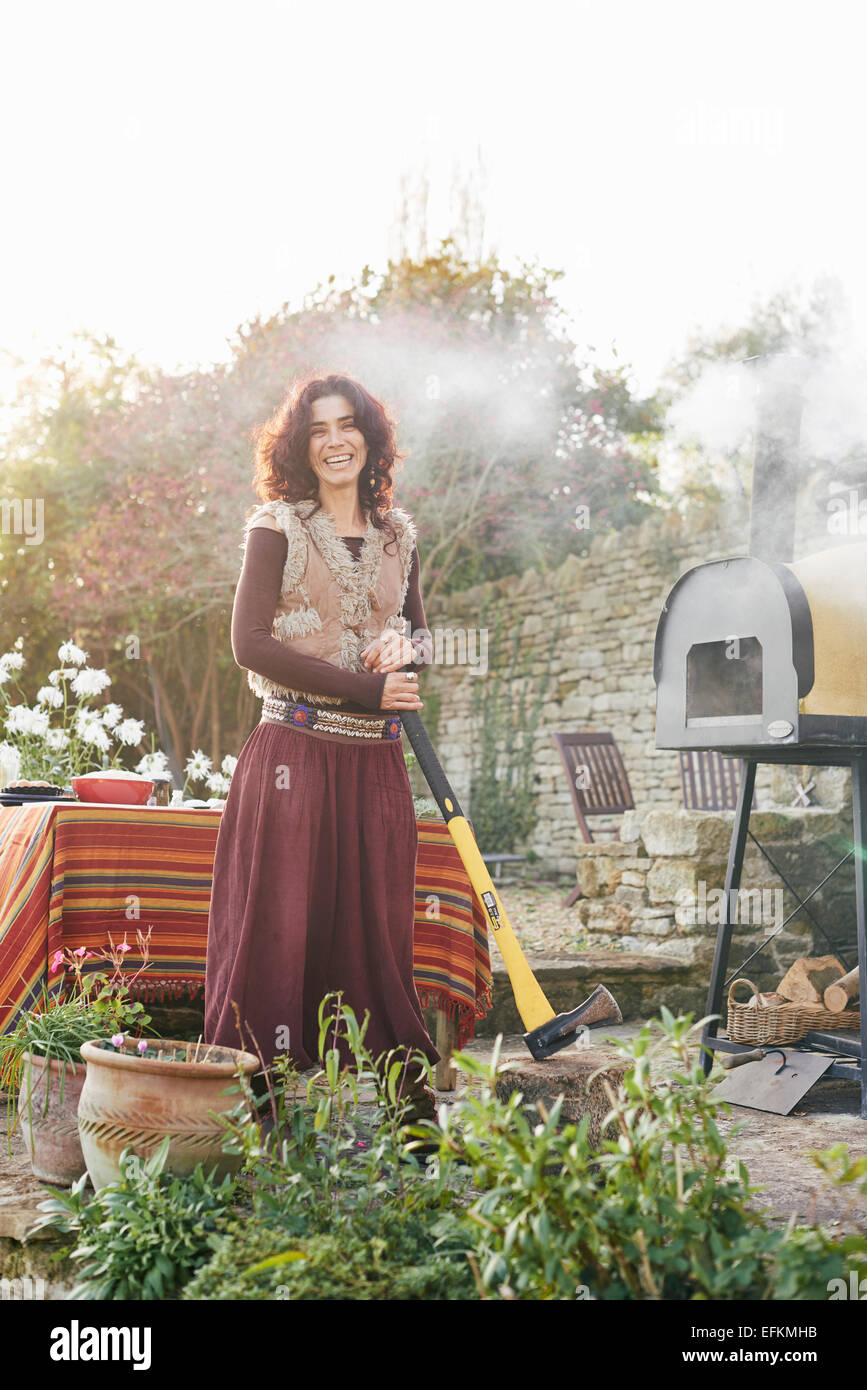 Portrait of mature femme hippie avec ax in garden Banque D'Images