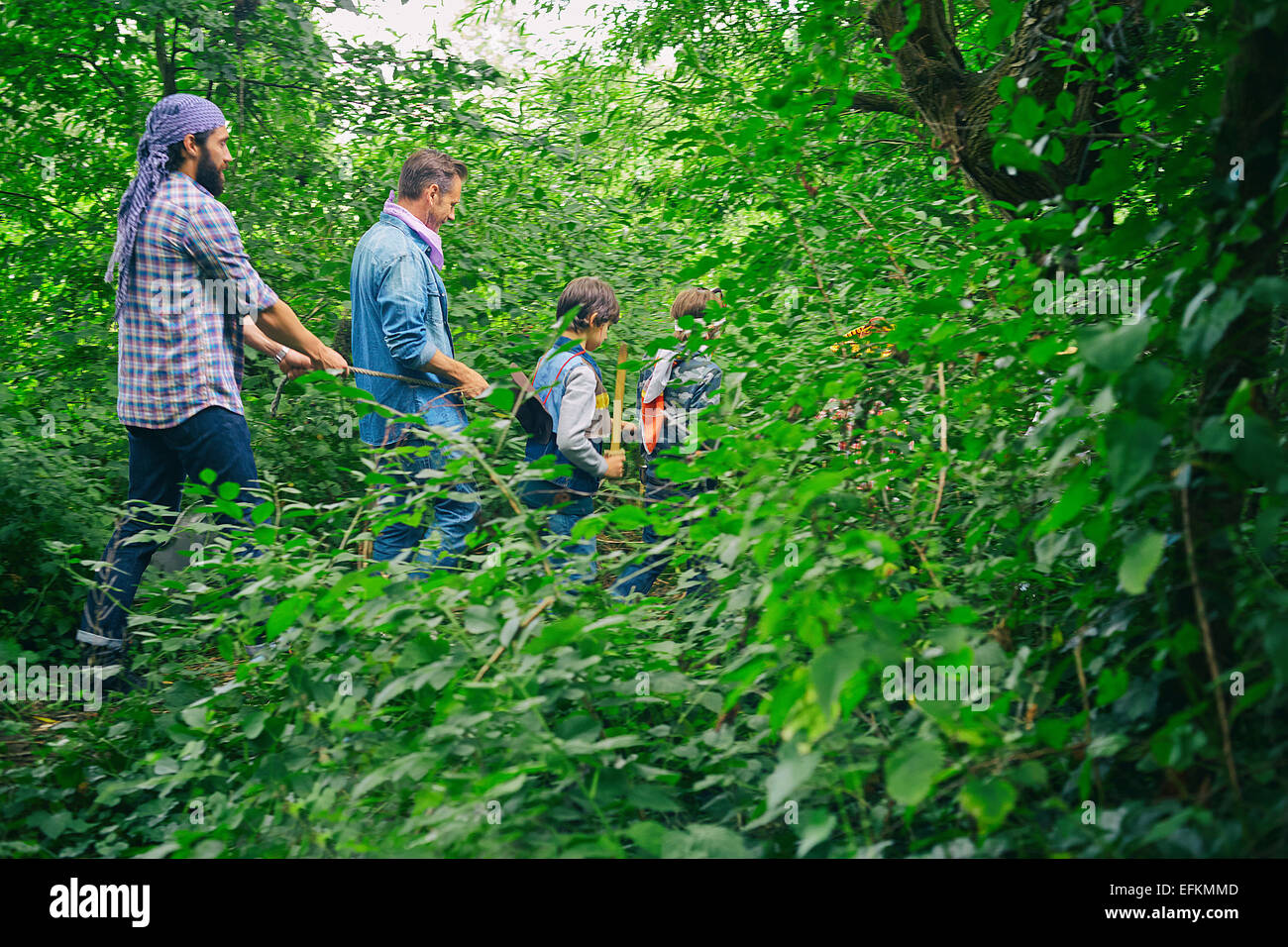 Deux hommes adultes et les garçons habillés et jouer dans la forêt Banque D'Images