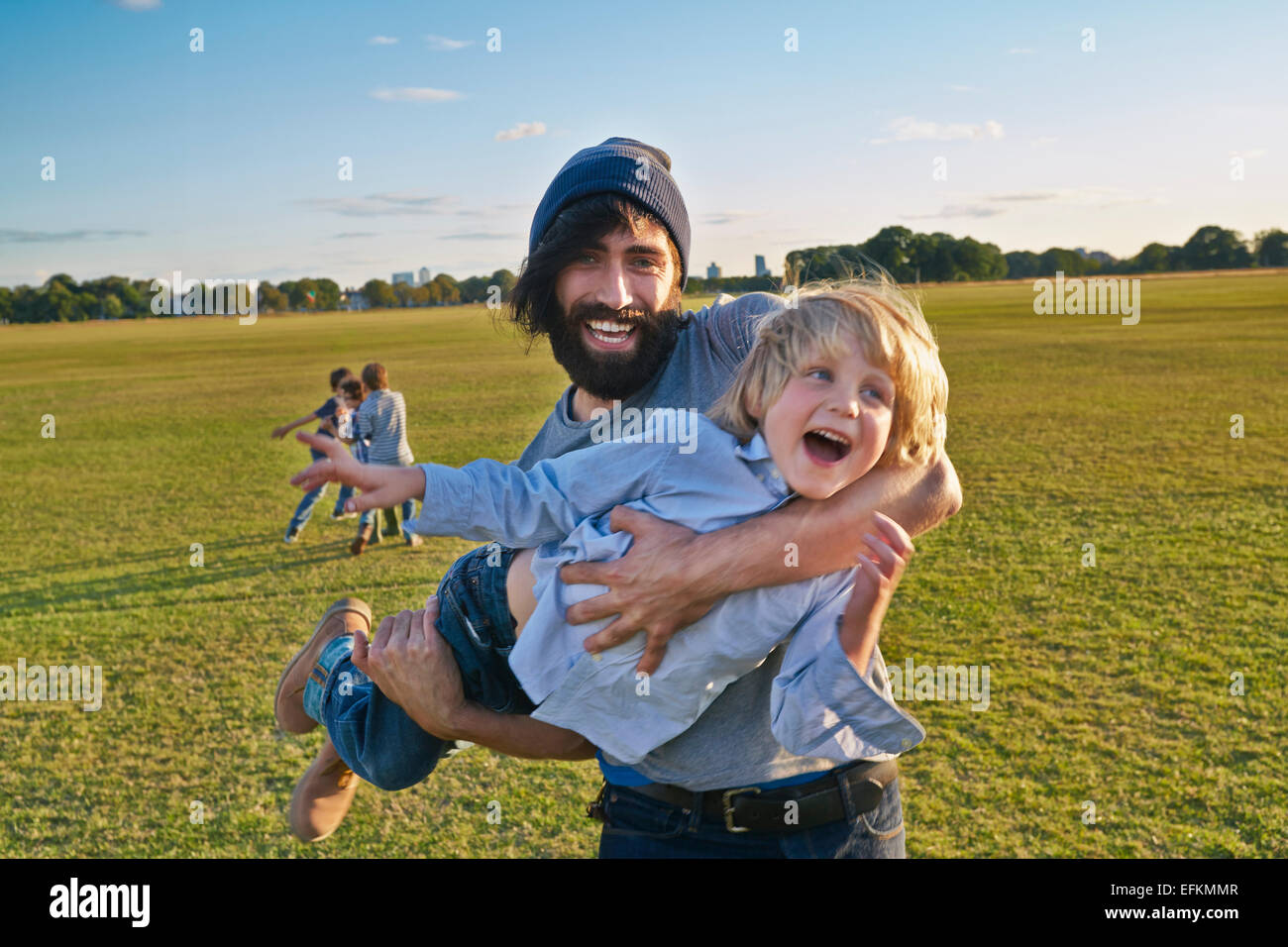 Mid adult man carrying son in field Banque D'Images