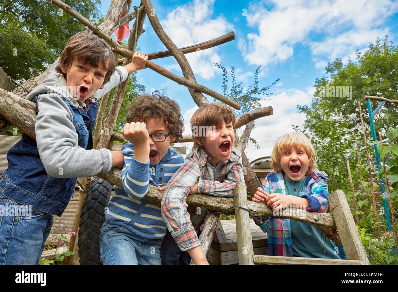 Quatre garçon crier sur des châssis d'escalade dans la région de jardin Banque D'Images