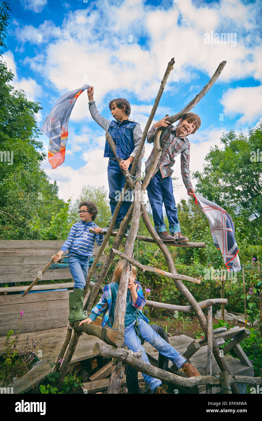 Quatre garçons d'Escalade sur mur d'escalade fait maison dans jardin Banque D'Images