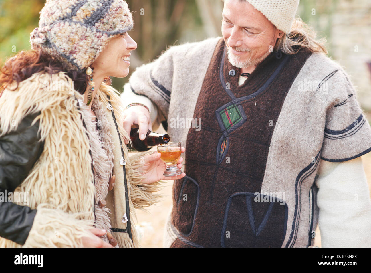 Hippy mature couple pouring verre de cidre dans le jardin Banque D'Images