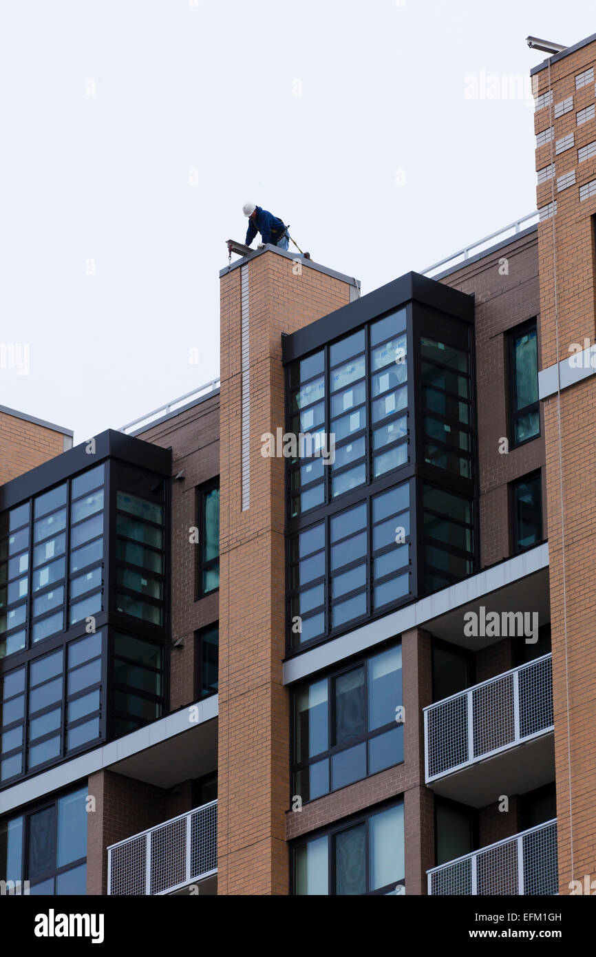 Man working on vire au sommet d'un immeuble d'habitation - USA Banque D'Images