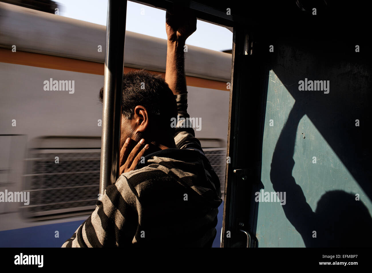 Un homme travaille sur un train de banlieue de Mumbai, Inde Banque D'Images