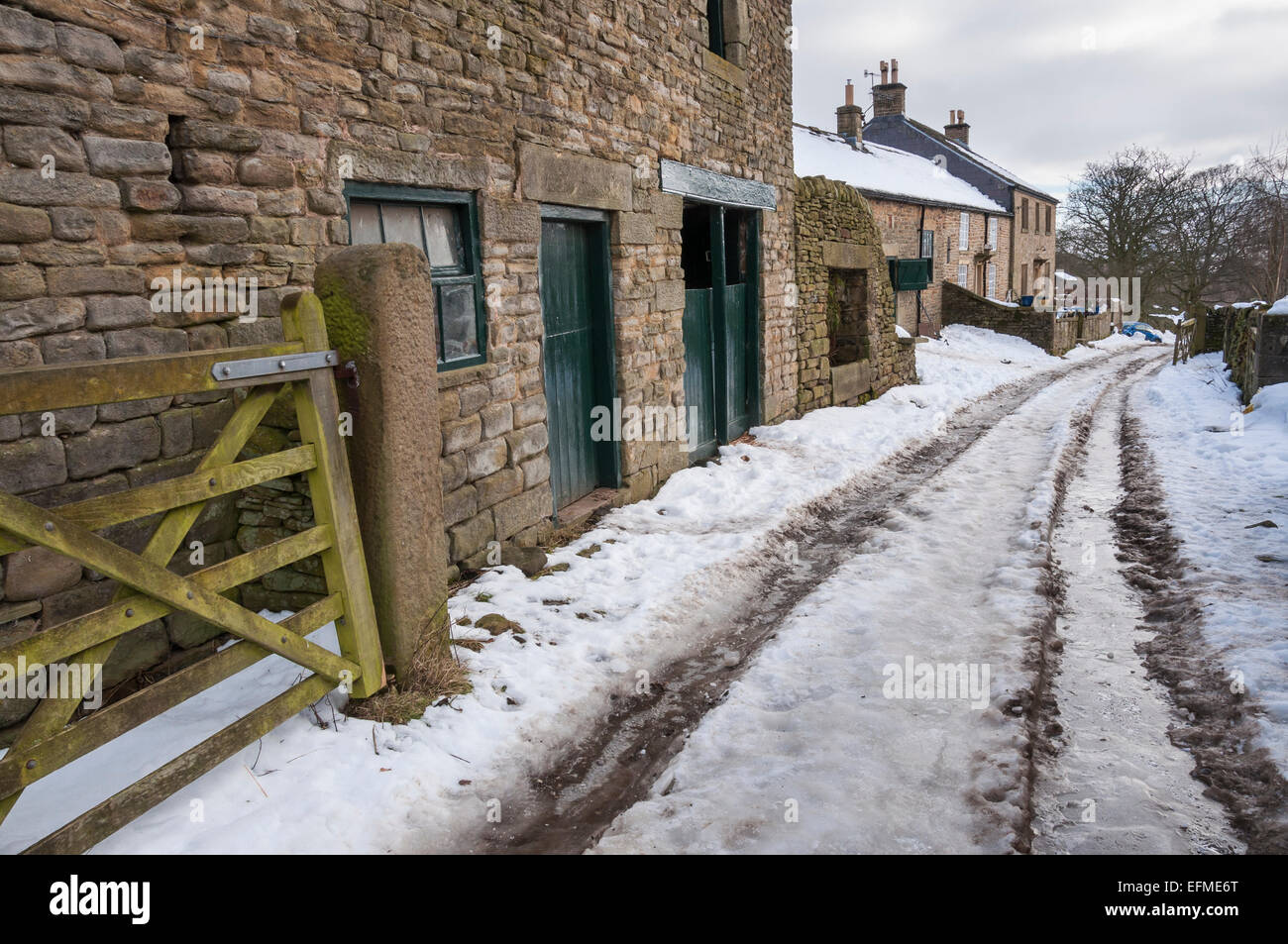 Une ferme de Peak District en hiver avec la neige a couvert la voie agricole et des bâtiments en pierre. Banque D'Images