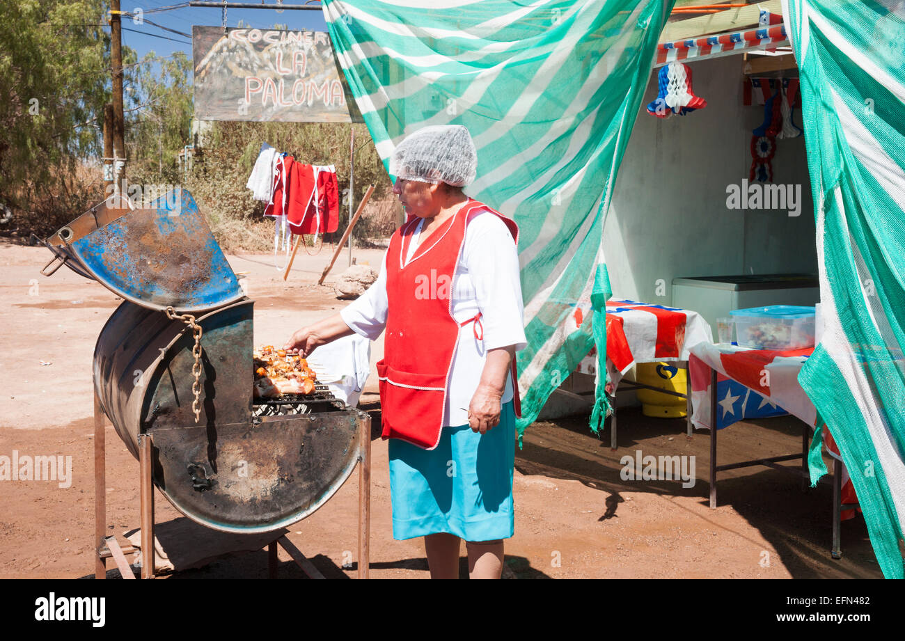 Une femme barbequeing la viande sur un grill à l'extérieur d'un restaurant pour la fête locale le 18 septembre, jour de l'indépendance, d'esprit Banque D'Images