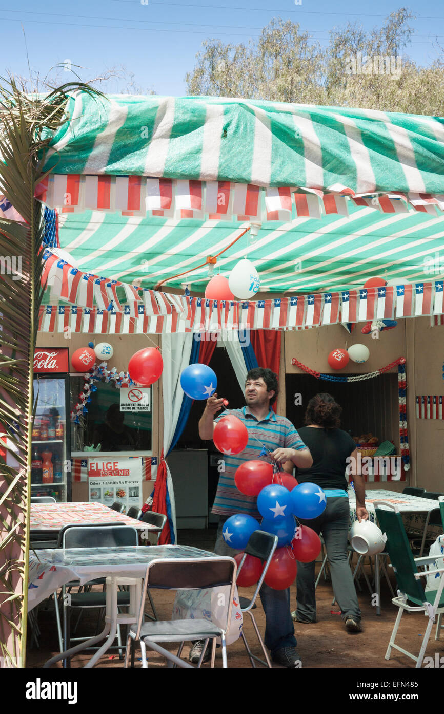 L'homme et la femme locale décorer leur restaurant en plein air pour le 18 septembre Jour de l'indépendance des fêtes avec des ballons et st Banque D'Images