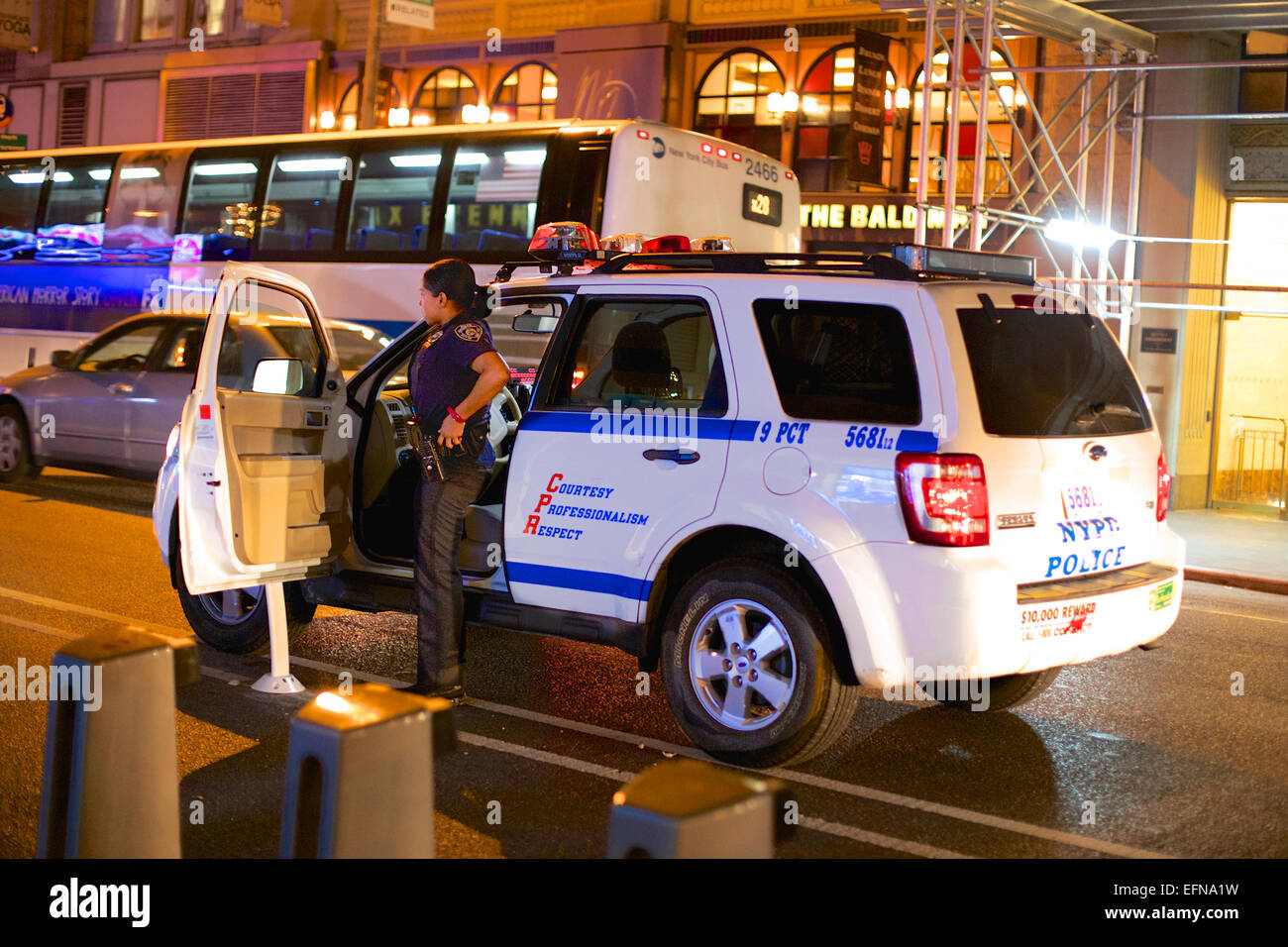 Agent de police de sexe féminin en sortant sa voiture le soir à New York, NY, USA. Banque D'Images