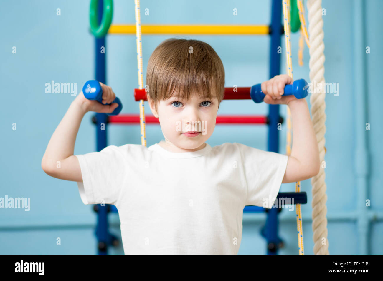 Strong kid boy exercising with dumbbells Banque D'Images