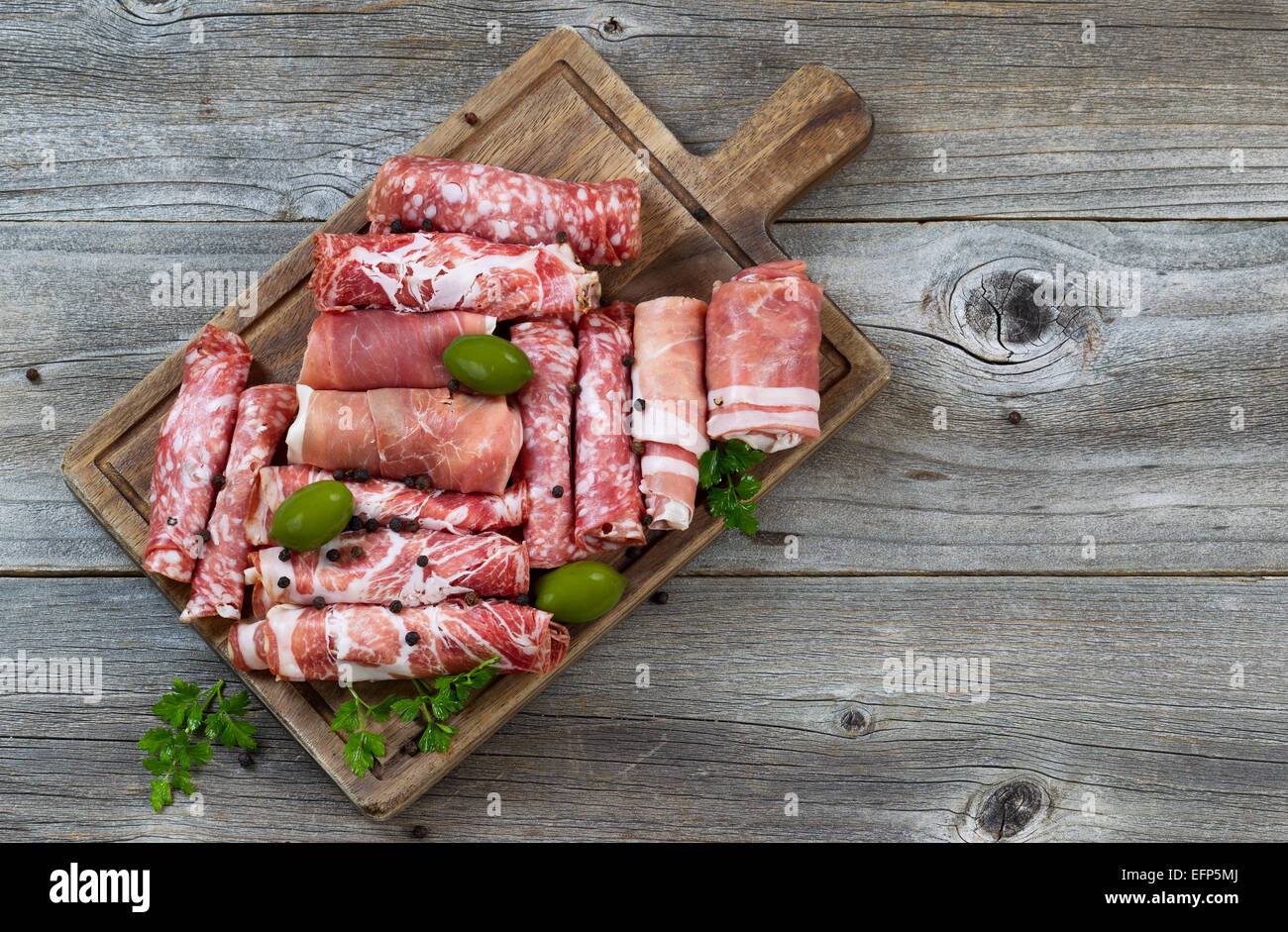 Vue de dessus horizontal image de viandes diverses sur le service à bord avec du jambon, du porc, du boeuf, de persil et d'olives sur bois rustique. Banque D'Images